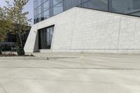 a white building has concrete walls and an empty parking lot with a small fire hydrant