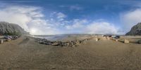 a fisheye lens photo of a car sitting on the beach in front of some rocks