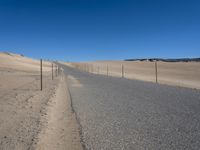 a paved beach with a fence in front of it and the ocean in the distance