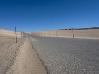 a paved beach with a fence in front of it and the ocean in the distance