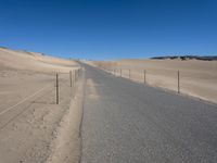 a paved beach with a fence in front of it and the ocean in the distance