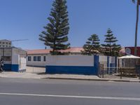 two motorcycles parked at a blue and white building with a tree in the front of it