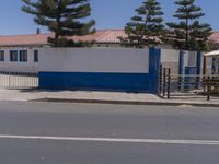 two motorcycles parked at a blue and white building with a tree in the front of it