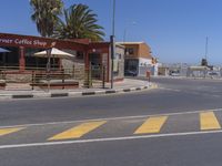 a street scene with no people at a coffee shop, and palm trees in the background