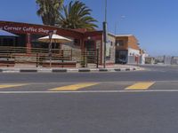 a street scene with no people at a coffee shop, and palm trees in the background