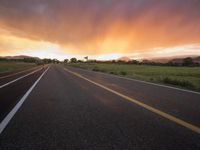 an empty highway in the open field at sunset with sun set in the distance behind it