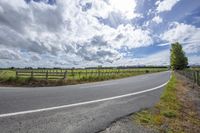 the highway winds up in the mountains between fields and vineyards fields in the distance with a blue sky and clouds above