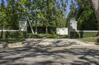 the sidewalk near the gate is lined with trees and shrubbery in a lush garden