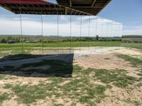 a picture of a glass pavilion over looking a farm field with a sky background and some cars