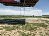 a picture of a glass pavilion over looking a farm field with a sky background and some cars