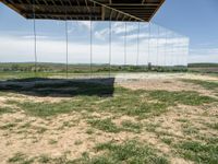 a picture of a glass pavilion over looking a farm field with a sky background and some cars