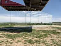 a picture of a glass pavilion over looking a farm field with a sky background and some cars