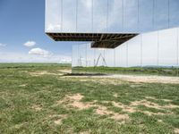 a mirrored photo taken over a grassy field near a metal object in the air, against a bright blue sky