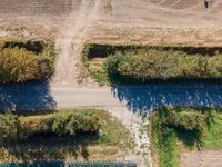 an aerial shot showing a farmer walking down the road in front of his crops and dirt area