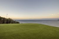 a beautiful view of the ocean and grass at dusk taken from an apartment overlooking the ocean