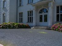 a large white house with a stone walkway leading up to the door and a blue fire hydrant at the end of one lane