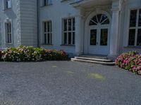 a large white house with a stone walkway leading up to the door and a blue fire hydrant at the end of one lane