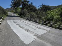 the top of the mountain is paved with cement pavement on the road and a wooden fence separates the street