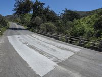 the top of the mountain is paved with cement pavement on the road and a wooden fence separates the street