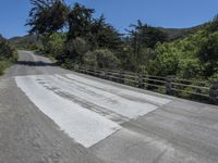 the top of the mountain is paved with cement pavement on the road and a wooden fence separates the street