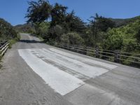 the top of the mountain is paved with cement pavement on the road and a wooden fence separates the street