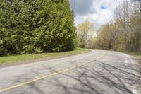 a wide road with an empty white and yellow curb surrounded by trees and grass on either side of the road