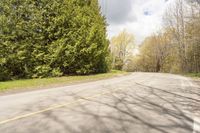 a wide road with an empty white and yellow curb surrounded by trees and grass on either side of the road