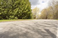 a wide road with an empty white and yellow curb surrounded by trees and grass on either side of the road