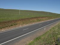 the country side is empty for traffic on the road with blue skies above it and green hills in the background