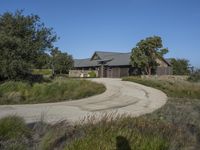 an old house is surrounded by lush green vegetation and a dirt road in front of it