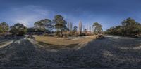 four vehicles that are driving on a grassy field with trees in the background and blue sky