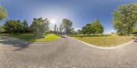 the 360 - panoramic image shows a road with trees on both sides and the sky