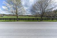 there is a field with a horse behind a fence at this spot in the middle of the road