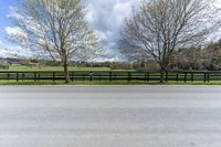 there is a field with a horse behind a fence at this spot in the middle of the road