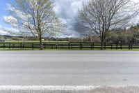 there is a field with a horse behind a fence at this spot in the middle of the road