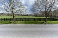 there is a field with a horse behind a fence at this spot in the middle of the road