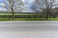 there is a field with a horse behind a fence at this spot in the middle of the road