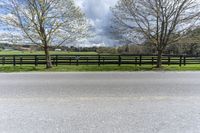 there is a field with a horse behind a fence at this spot in the middle of the road