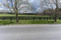 there is a field with a horse behind a fence at this spot in the middle of the road