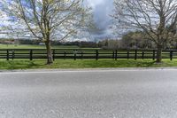 there is a field with a horse behind a fence at this spot in the middle of the road