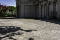 a picture of a driveway lined with trees and buildings behind it and a bench on either side of the area