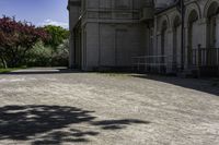 a picture of a driveway lined with trees and buildings behind it and a bench on either side of the area