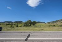 the empty road is going along with the mountains in the background, and there are white clouds