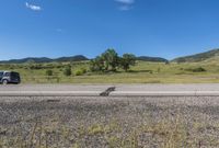 the empty road is going along with the mountains in the background, and there are white clouds