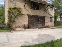 a building with an outside bench on the cement floor and window frames and a brick wall