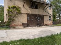 a building with an outside bench on the cement floor and window frames and a brick wall