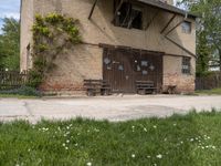 a building with an outside bench on the cement floor and window frames and a brick wall