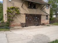 a building with an outside bench on the cement floor and window frames and a brick wall