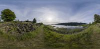 an image of a view from a fisheye lens of the water, and hills,