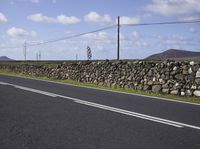 a single vehicle is traveling along an empty road in a remote area with telephone lines